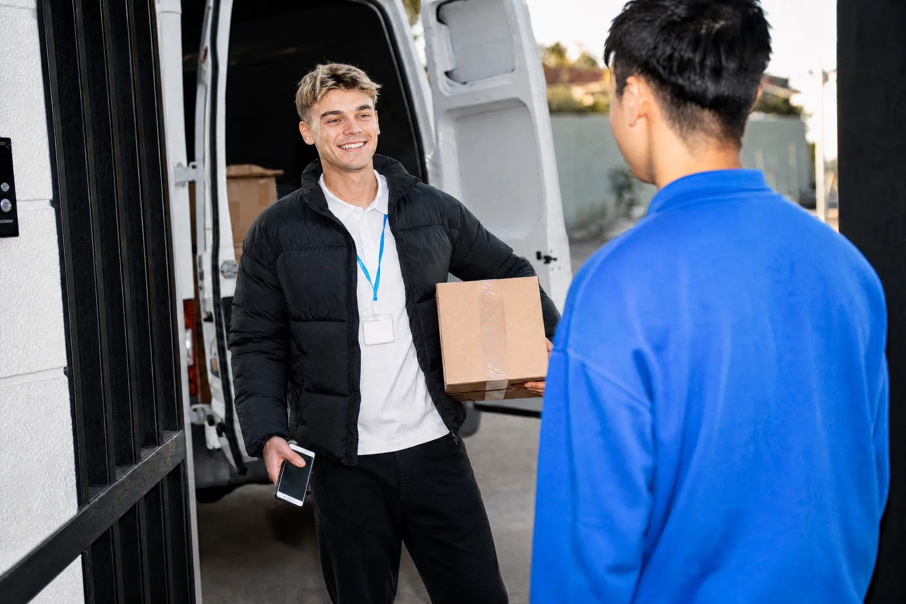 Courier handing a parcel to a customer at a delivery van Courier handing a parcel to a customer at a delivery van